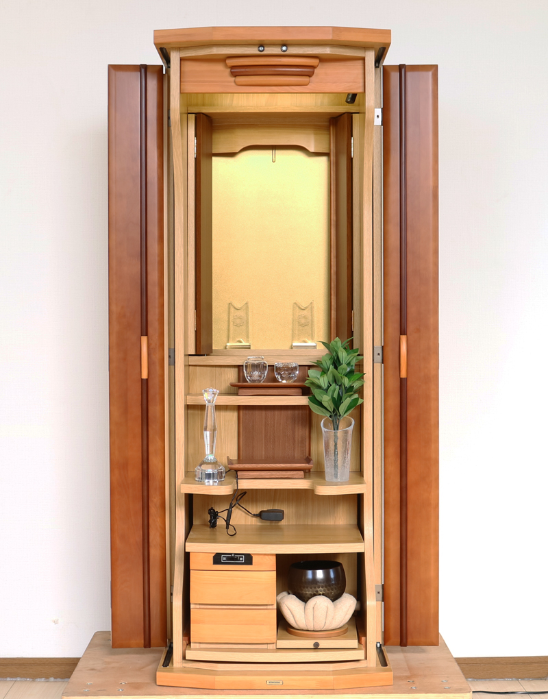 ダーク色とライト色のツートンのコンビネーション色です。今までのお仏壇のデザインではなかった、オシャレな雰囲気漂うデザインに仕上がっております。  材質はデザインにあった、パイン材を使用しており、暖かみあふれる明るい印象をお部屋にプラスしてくれます。  金剛堂アンサンブル現在でも販売されているお仏壇です。    製品名 	創価学会中古仏壇639 設置 	和室・洋室・拠点・ワンルーム・一人暮らしにも最適です 種別 	家具調仏壇 サイズ 	  仏壇全体:高さ145cm x 幅54cm x 奥行き49cm  扉二つ折り最大幅:79cm  厨子内寸: 52cm x 32cm 	  材質 	芯材:MDF、扉:パイン材、 機能 	  自動扉・引き出し3箇所(厨子下一個、下部引き出し二個)、収納経机