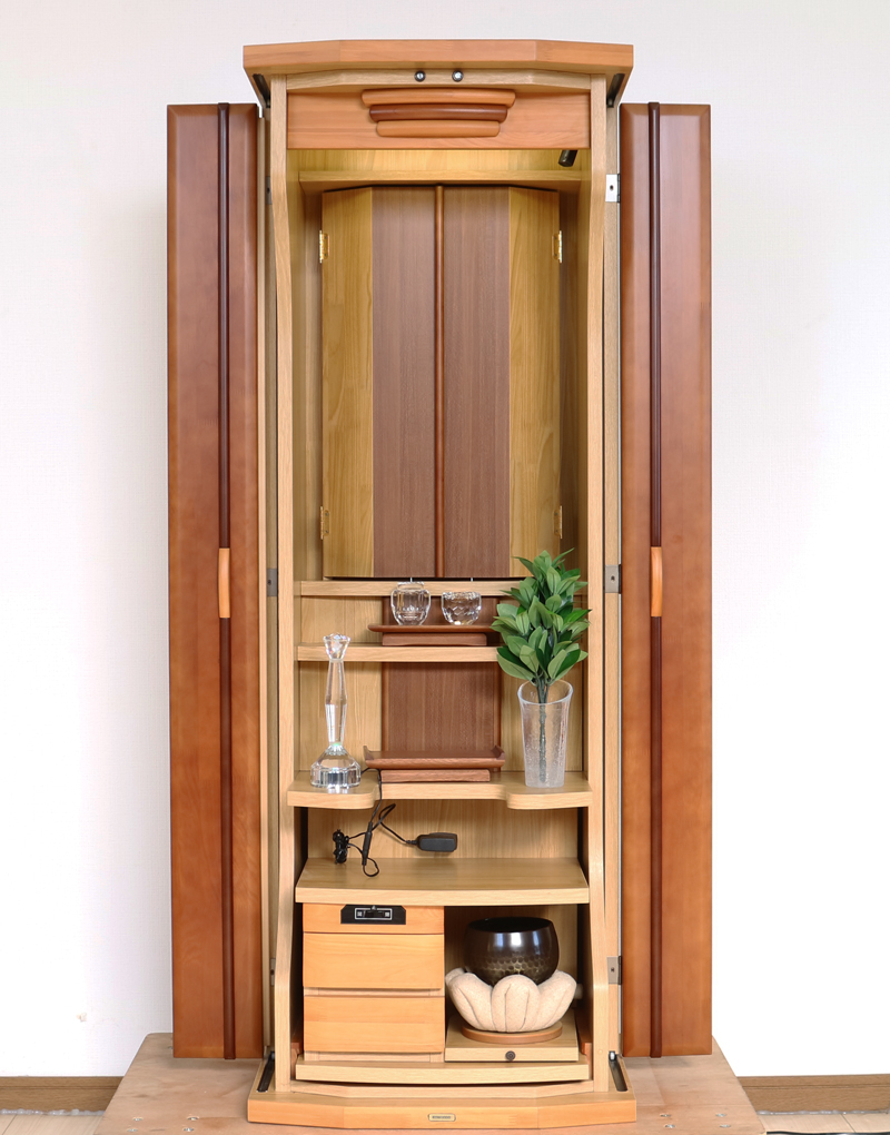 ダーク色とライト色のツートンのコンビネーション色です。今までのお仏壇のデザインではなかった、オシャレな雰囲気漂うデザインに仕上がっております。  材質はデザインにあった、パイン材を使用しており、暖かみあふれる明るい印象をお部屋にプラスしてくれます。  金剛堂アンサンブル現在でも販売されているお仏壇です。    製品名 	創価学会中古仏壇639 設置 	和室・洋室・拠点・ワンルーム・一人暮らしにも最適です 種別 	家具調仏壇 サイズ 	  仏壇全体:高さ145cm x 幅54cm x 奥行き49cm  扉二つ折り最大幅:79cm  厨子内寸: 52cm x 32cm 	  材質 	芯材:MDF、扉:パイン材、 機能 	  自動扉・引き出し3箇所(厨子下一個、下部引き出し二個)、収納経机