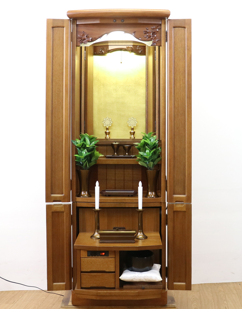 金剛堂製の二段重ねの家具調電動仏壇です。厨子上部に二重の桜の彫刻はオシャレな雰囲気漂うデザインに仕上がっております。  材質はデザインにあった、マホガニー材を使用しており、暖かみあふれる明るい印象をお部屋にプラスしてくれます。  和室・洋室・リビングダイニングにも最適です。また厨子内は、金箔を使用しておりご本尊様を明るく荘厳いたします。 製品名 	創価学会　家具調電動中古仏壇　643　金剛堂製 設置 	和室・洋室・拠点にも最適です 種別 	中古家具調仏壇 サイズ 	  仏壇全体:高さ約150cm x 幅約53cm x 奥行き約49cm  厨子内寸:約51cm x 約35cm (特装ご本尊様可能) 	  材質 	マホガニー無垢、貼り、合成杢、MDF 機能 	  自動開閉厨子・蛍光照明・厨子内金箔