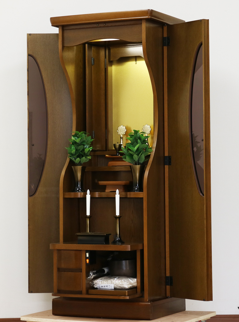 今までのお仏壇のデザインではなかった、オシャレな雰囲気漂うデザインに仕上がっております。暖かみあふれる明るい印象をお部屋にプラスしてくれます。 外扉は、スモークガラス入りの斬新なデザインです。 外扉を開けると、曲線美を意識した丸みを帯びた厨子扉と厨子下収納がございます。ならの天然杢を使用した上品な仕上がりのお仏壇です。 仏壇全体:高さ約162cm x 幅約58cm x 奥行約47.5cm