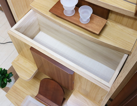  ダーク色とライト色のツートンのコンビネーション色です。今までのお仏壇のデザインではなかった、オシャレな雰囲気漂うデザインに仕上がっております。  材質はデザインにあった、パイン材を使用しており、暖かみあふれる明るい印象をお部屋にプラスしてくれます。  金剛堂アンサンブル現在でも販売されているお仏壇です。    製品名 創価学会中古仏壇709 設置 	和室・洋室・拠点・ワンルーム・一人暮らしにも最適です 種別 	家具調仏壇 サイズ 	  仏壇全体:高さ145cm x 幅54cm x 奥行き49cm  扉二つ折り最大幅:79cm  厨子内寸: 52cm x 32cm 	  材質 	芯材:MDF、扉:パイン材、 機能 	  自動扉・引き出し3箇所(厨子下一個、下部引き出し二個)、収納経机