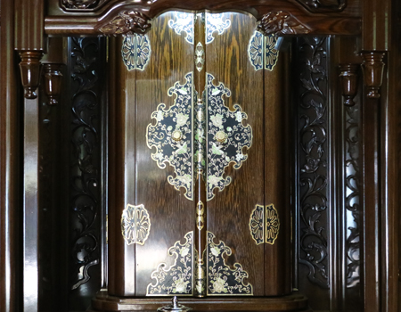 創価学会仏壇専門店桜梅桃李.comより発売いたします、会場拠点用鉄刀木　伝統型押込み扉仏壇KB004です。  経机・花台・リン台付きで、本格的なお仏壇となります。 製品名 	  創価学会中古仏壇　KB004 設置 	和室・洋室・拠点・男子部拠点にも最適です 種別 	厨子型電動仏壇 サイズ 	   仏壇本体　高さ:約173cm ×幅:約91cm×奥行:約74cm  扉最大の幅:約48cm  厨子内　高さ:約60cm×幅:約37cm  経机　高さ:約41cm×幅:約78cm×奥行:約41cm 	  材質 	鉄刀木・貼り・無垢・MDF 機能 	  スイッチ式電動扉  経机引き出し2箇所・仏壇本体引き出し4か所　計6箇所  掲載仏具一式付き(造花しきみ二本・仏器茶器のみ新品)  厨子背板を、新品の金吹きの塗装板に替えました。