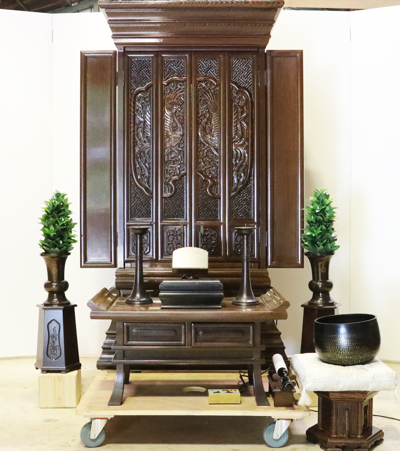 創価学会仏壇専門店桜梅桃李.comより発売いたします、会場拠点用鉄刀木　伝統型押込み扉仏壇KB004です。  経机・花台・リン台付きで、本格的なお仏壇となります。 製品名 	  創価学会中古仏壇　KB004 設置 	和室・洋室・拠点・男子部拠点にも最適です 種別 	厨子型電動仏壇 サイズ 	   仏壇本体　高さ:約173cm ×幅:約91cm×奥行:約74cm  扉最大の幅:約48cm  厨子内　高さ:約60cm×幅:約37cm  経机　高さ:約41cm×幅:約78cm×奥行:約41cm 	  材質 	鉄刀木・貼り・無垢・MDF 機能 	  スイッチ式電動扉  経机引き出し2箇所・仏壇本体引き出し4か所　計6箇所  掲載仏具一式付き(造花しきみ二本・仏器茶器のみ新品)  厨子背板を、新品の金吹きの塗装板に替えました。