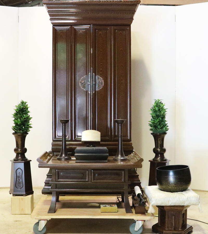 創価学会仏壇専門店桜梅桃李.comより発売いたします、会場拠点用鉄刀木　伝統型押込み扉仏壇KB004です。  経机・花台・リン台付きで、本格的なお仏壇となります。 製品名 	  創価学会中古仏壇　KB004 設置 	和室・洋室・拠点・男子部拠点にも最適です 種別 	厨子型電動仏壇 サイズ 	   仏壇本体　高さ:約173cm ×幅:約91cm×奥行:約74cm  扉最大の幅:約48cm  厨子内　高さ:約60cm×幅:約37cm  経机　高さ:約41cm×幅:約78cm×奥行:約41cm 	  材質 	鉄刀木・貼り・無垢・MDF 機能 	  スイッチ式電動扉  経机引き出し2箇所・仏壇本体引き出し4か所　計6箇所  掲載仏具一式付き(造花しきみ二本・仏器茶器のみ新品)  厨子背板を、新品の金吹きの塗装板に替えました。